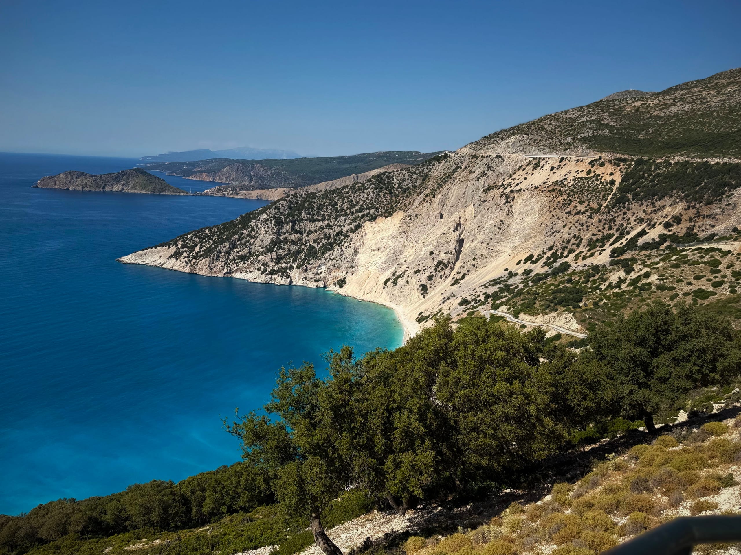 The coast road high above Myrtos bay on Kefalonia, white cliffs and headlands stacked to the horizon
