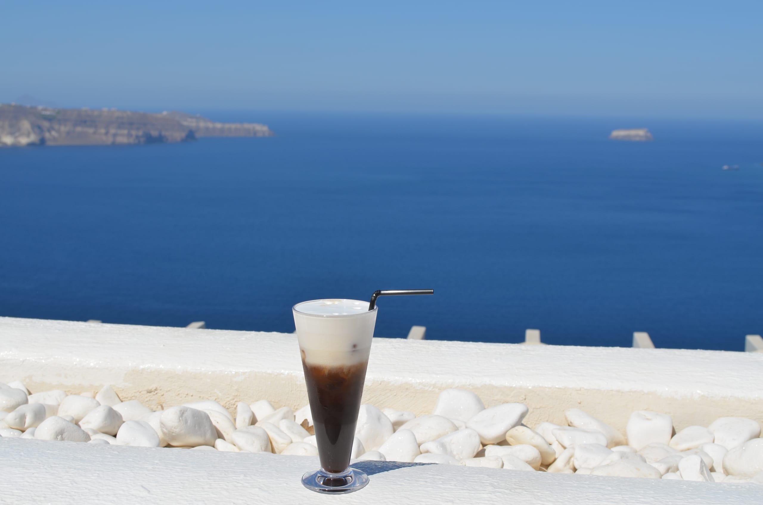 A freddo cappuccino on a whitewashed wall above the Aegean, Santorini