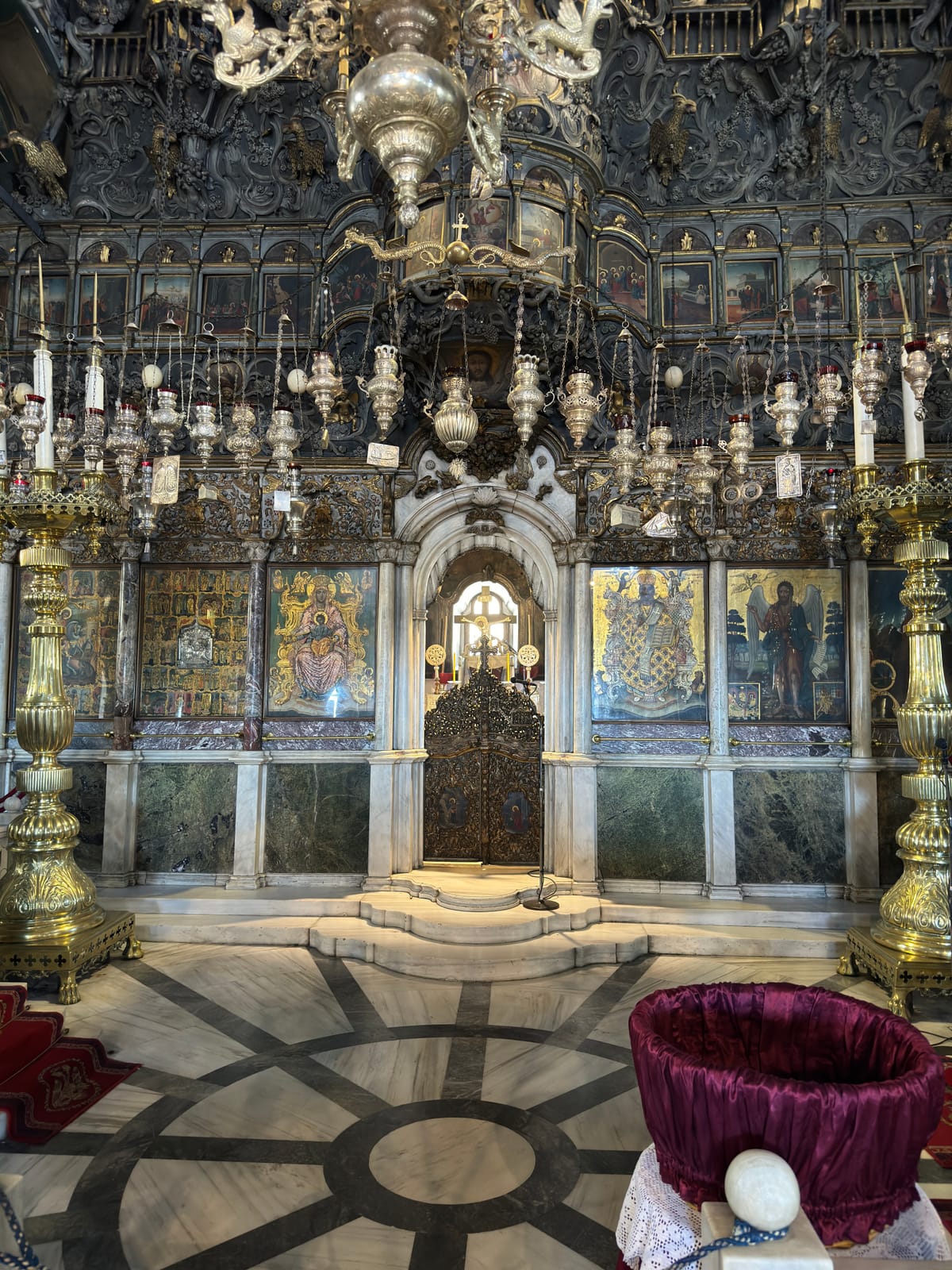 The marble floor of Panagia Evangelistria, a dark radial inlay running toward the sanctuary steps and the iconostasis beyond